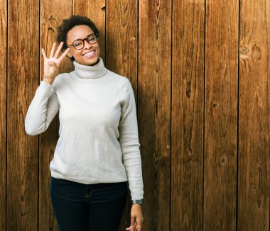 Genç güzel Afrikalı-Amerikalı kadın gözlük gösterilen ve parmakları ile işaret izole arka plan üzerinde dört kendinden emin ve mutlu gülümseyerek iken numara.