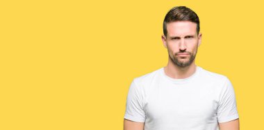 Casual beyaz t-shirt şüpheci ve sinir, papatyanın üzgün sorunu nedeniyle giyen yakışıklı adam. Negatif kişi.