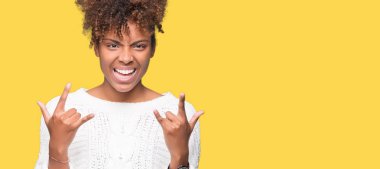 Deli ifade rock simge elle yapıyor ile bağırarak izole arka plan üzerinde kış kazak giyen güzel genç Afro-Amerikan kadın. Müzik yıldızı. Ağır kavramı.