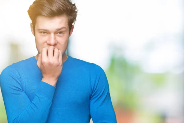孤立した背景の上に青いセーターを着た若いハンサムな男は 口を噛む爪に手を当て ストレスと緊張しているように見えます 不安の問題 — ストック写真