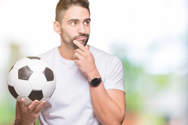 Молодой Человек Держит Футбольный Мяч Изолированном Фоне Серьезное Лицо Думая — стоковое фото