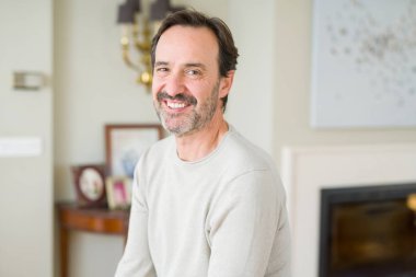 Evde kameraya bakarak gülümseyen yakışıklı orta yaş erkek