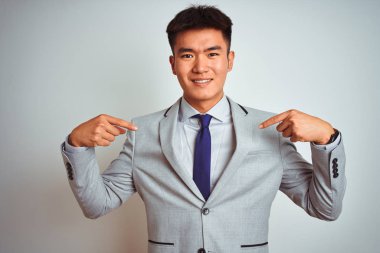 Asyalı Çinli işadamı takım elbise ve kravat izole sarı arka plan üzerinde duran yüzünde gülümseme ile emin görünümlü, parmakları gururlu ve mutlu kendini işaret.