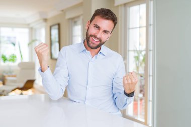 Yakışıklı iş adamı şaşırmış kutluyor ve kollarını kaldırdı ve gözleri açık başarı için şaşırttı. Kazanan kavramı.