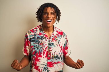 Izole beyaz arka plan üzerinde yazlık gömlek giyen tatilde dreadlocks ile Afro adam şaşırmış kutluyor ve kollarını kaldırdı ve açık gözleri ile başarı için şaşırttı. Kazanan kavramı.