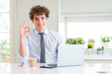 Ofiste bilgisayar dizüstü bilgisayar ile çalışan genç iş adamı parmakları ile ok işareti yapıyor, mükemmel sembolü