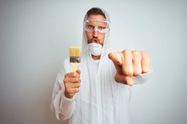 Kamera ve size parmak ile işaret izole arka plan üzerinde fırça tutan profesyonel işçi ekipmanları giyen ressam adam, el işareti, önden olumlu ve kendinden emin jest