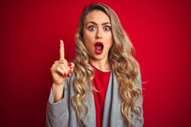 Genç güzel iş kadını başarılı bir fikir ile parmak işaret kırmızı izole arka plan üzerinde duran zarif ceket giyiyor. Çıktı ve mutlu. Bir numara.