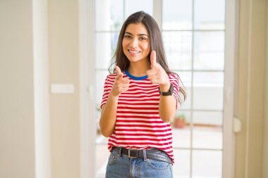 Fotoğraf makinesi ile mutlu ve komik yüz için rahat t-shirt işaret parmakları giyen genç güzel kadın. İyi enerji ve vibes.
