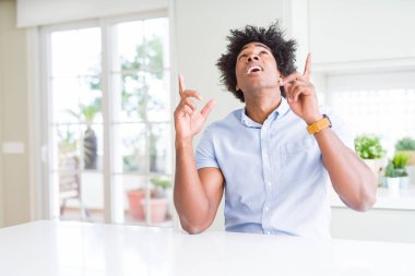 Afro-Amerikan iş adamı şaşırttı ve yukarı bakarak şaşırttı ve parmakları ile işaret ve kollarını kaldırdı.