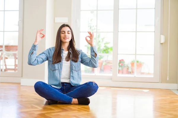 坐在家里地板上的美丽的年轻女子放松了 闭着眼睛用手指做冥想手势 面带微笑 瑜伽概念 — 图库照片