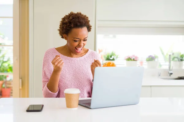 年轻的非洲美国妇女使用计算机笔记本电脑工作非常高兴和兴奋做赢家的手势与手臂抬起 微笑着 尖叫着要成功 庆祝理念 — 图库照片
