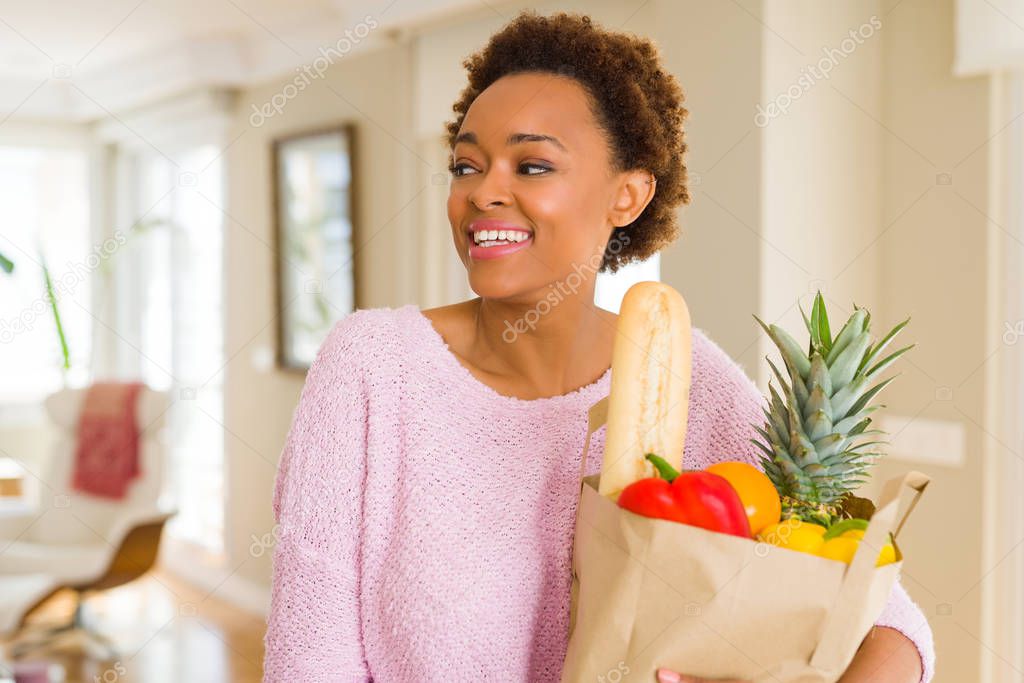 Young beautiful african american woman holding paper bag full of