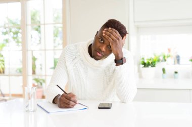 Afro-Amerikan öğrenci adam bir kalem kullanarak bir kalem kullanarak baş el ile vurguladı, utanç ve sürpriz yüz ile şok, kızgın ve sinirli. Korku ve hata için üzgün.