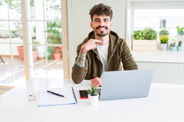 Bilgisayar laptop ve defter sürpriz yüz işaret parmağı kendisine kullanan genç öğrenci adam