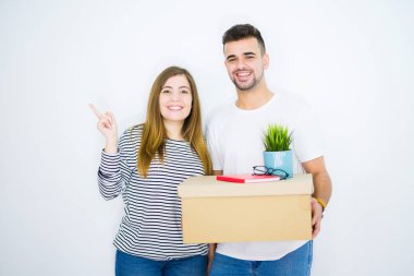 Genç çift karton kutu tutan beyaz izole arka plan üzerinde yeni bir eve hareket çok mutlu yan el ve parmak ile işaret
