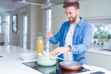 Evde makarna pişiren yakışıklı adam.