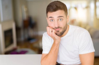 Evde rahat beyaz t-shirt giyen genç yakışıklı adam yorgun bakıyor ve çapraz silah ile depresyon sorunları ile sıkılmış düşünme.