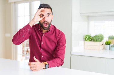 Yakışıklı İspanyol iş adamı ok jest yapıyor şaşırmış yüzü ile şok, göz parmaklarından bakarak. İnanmayan ifade.