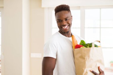 Afro-amerikan adam bakkal dolu kağıt torba tutan mutlu bir