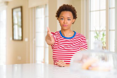 Tebrik ve konuksever dost sunan karşılıklı gülümseyen genç güzel Afrikalı-Amerikalı kadın evde. Başarılı iş.