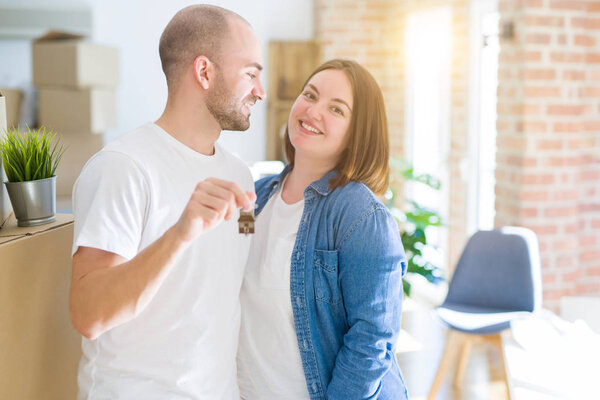 Young couple smiling very happy showing keys of new home, moving