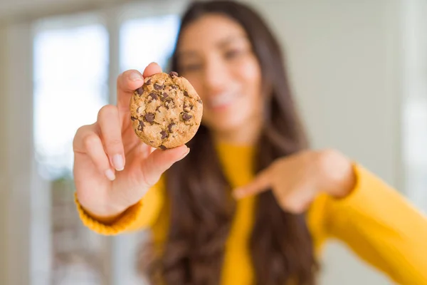 Junge Frau Isst Hause Kekse Mit Überraschungsgesicht Und Zeigt Mit — Stockfoto