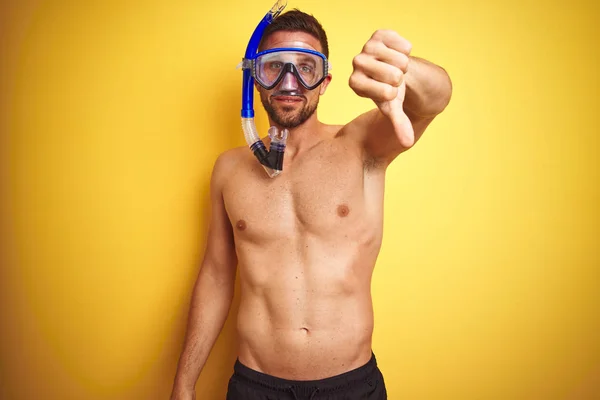 年轻英俊的无衬衫男子穿着潜水护目镜在孤立的黄色背景与愤怒的脸 负面标志显示不喜欢与拇指向下 拒绝概念 — 图库照片