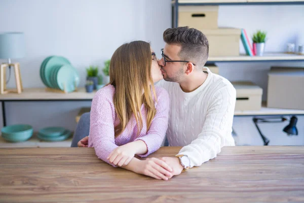 Young beautiful couple sitting on the table at home, hugging in