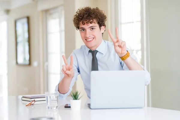 在办公室工作的年轻商人微笑着看着相机显示手指做胜利标志 — 图库照片