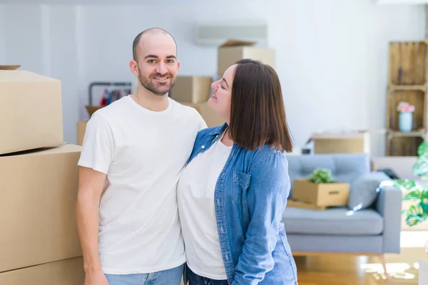 Pareja joven juntos sonriendo feliz mudándose a una nueva casa —  Fotos de Stock