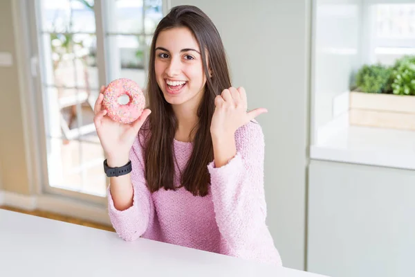 ピンクのチョコチップを食べる美しい若い女性が指差し 幸せそうな顔で横に親指で見せる — ストック写真