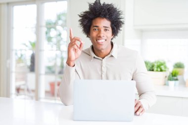 Afro-Amerikan adam mutlu yüz, bir numaralı ile bir fikir veya soru işaret parmağı ile şaşırttı dizüstü bilgisayar kullanarak çalışan