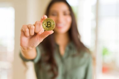 Bitcoin kriptoparalarını elektronik olarak tutarak gülümseyen genç kadın