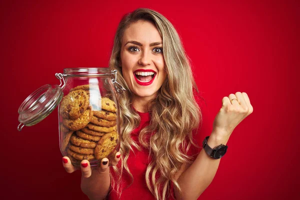 Jovem Bela Mulher Segurando Frasco Biscoitos Sobre Fundo Isolado Vermelho — Fotografia de Stock