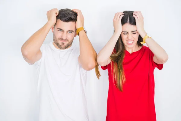 若い美しいカップルは 痛みと偏頭痛のために絶望的な頭痛に苦しむ白い孤立した背景の上に一緒に 頭の上に手を置く — ストック写真