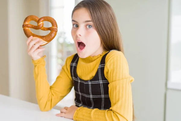 ドイツのスナック塩辛いプレッツェルを食べる美しい若い女の子は 驚きの顔でショックを受け 恐怖表現で恐怖と興奮 — ストック写真