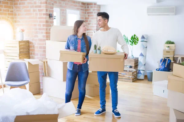 Schönes junges asiatisches Paar sieht glücklich aus, als es Pappschachtel hält — Stockfoto