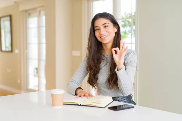 Mujer Joven Leyendo Libro Bebiendo Café Haciendo Signo Con Los —  Fotos de Stock