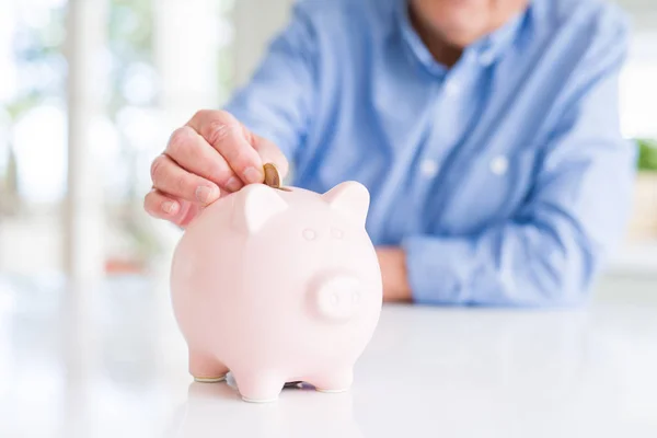 Close up van de man brengen van een munt binnenkant piggy bank als besparingen — Stockfoto