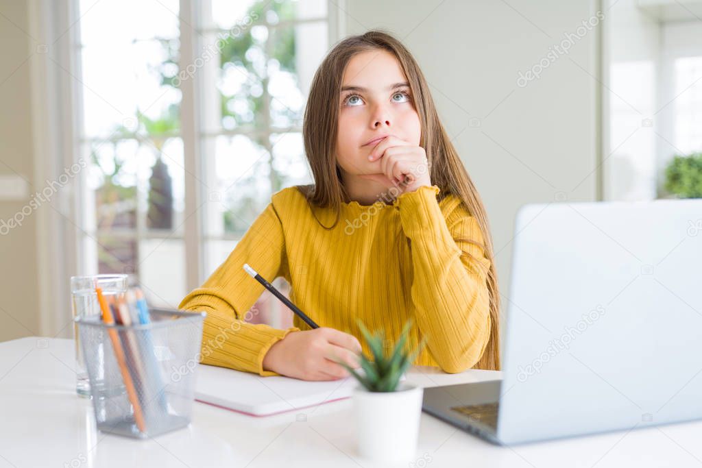 Beautiful young girl studying using computer laptop and writing on notebook serious face thinking about question, very confused idea
