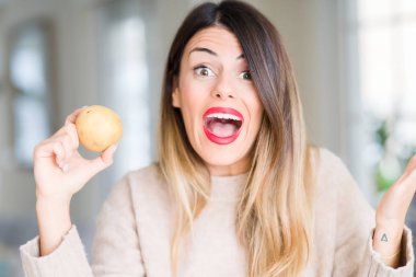 Taze patates evde çok mutlu ve heyecanlı, kocaman bir gülümseme ile çığlık zaferini kutluyor kazanan ifade tutarak ve ellerini kaldırdı genç güzel kadın