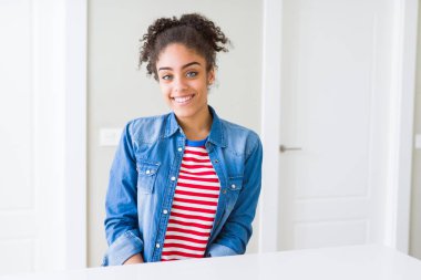 Yüzünde mutlu ve güzel bir gülümseme ile rahat denim ceket giyen afro saçlı güzel genç Afro-Amerikan kadın. Şanslı kişi.