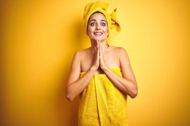 Güzel kadın vücut ve sarı izole arka plan üzerinde baş giyen elleri birlikte emin gülümseyerek af isteyen dua.