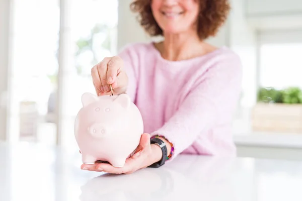 Primer plano de la mujer mayor poniendo una moneda dentro de la alcancía como sav — Foto de Stock