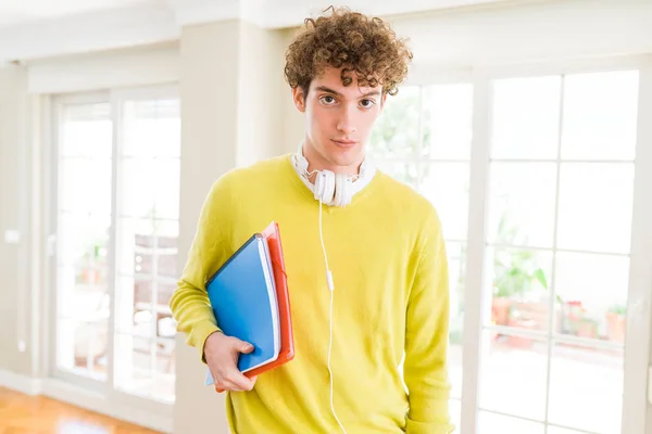 年轻的学生男子戴着耳机 拿着笔记本 在聪明的脸上表情自信认真思考 — 图库照片