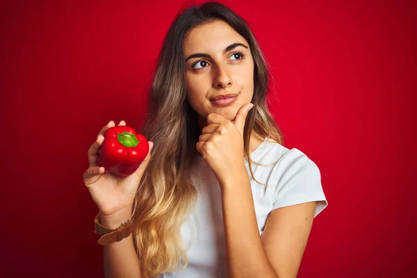 Giovane Bella Donna Possesso Pepe Sfondo Rosso Isolato Volto Serio — Foto Stock