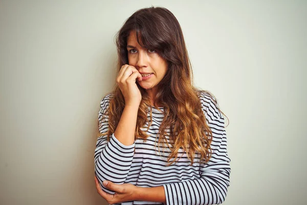 白い孤立した背景の上にストライプTシャツを着た若い美しい女性は 口を噛む爪に手を当てて ストレスと緊張を見ています 不安の問題 — ストック写真