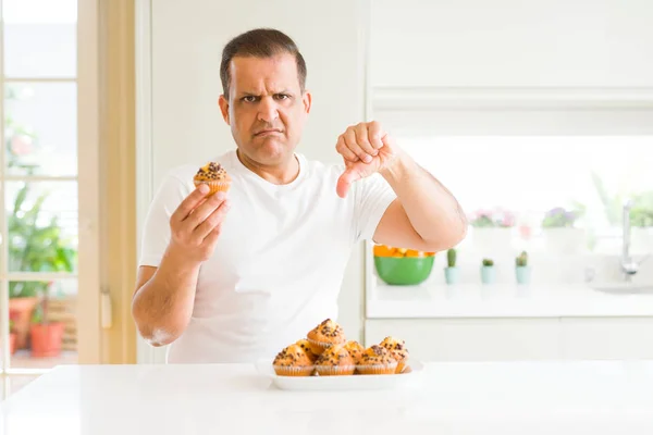 Middelbare Leeftijd Man Eten Chocolade Chip Muffins Thuis Met Boos — Stockfoto