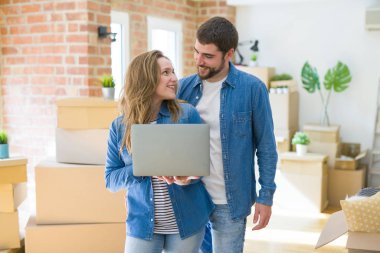 Genç çift araba etrafında bir odada duran bilgisayar dizüstü bilgisayar kullanarak